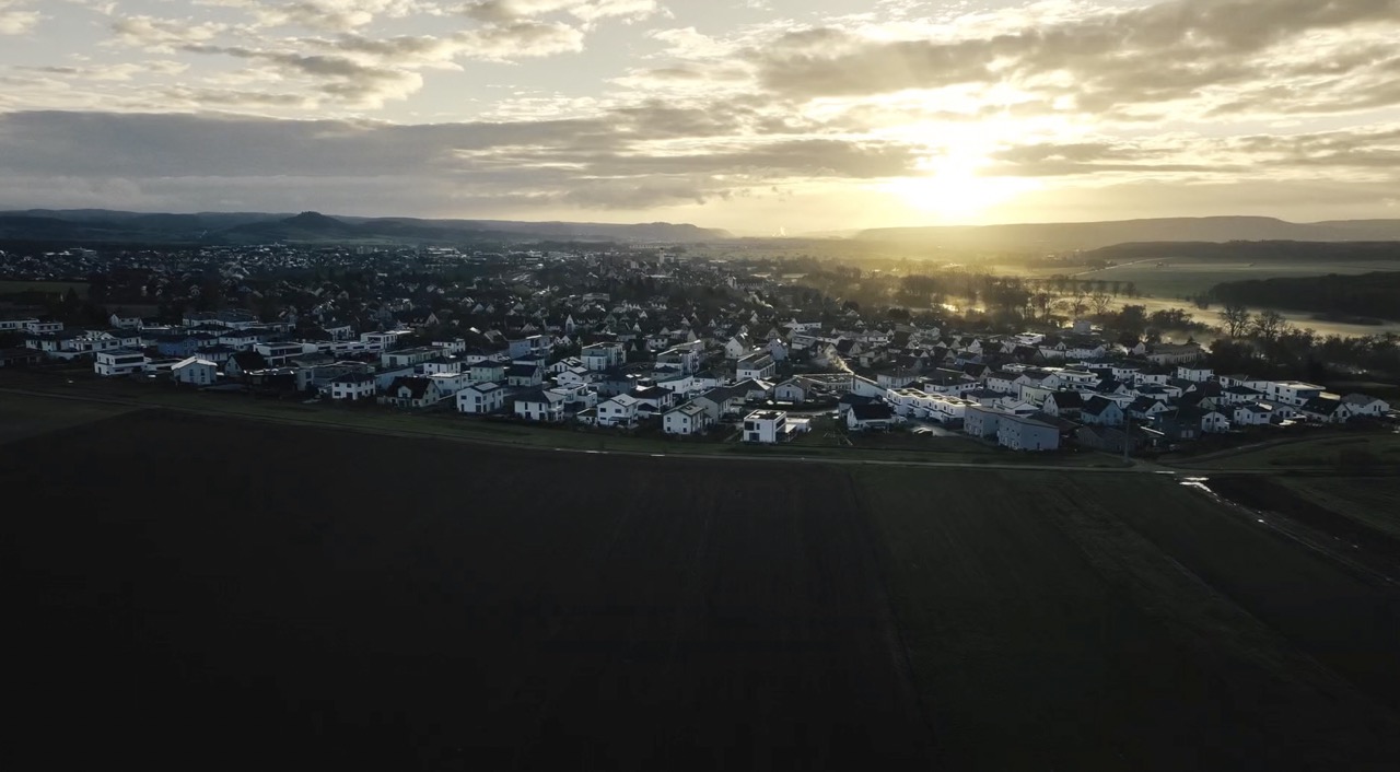 Drohnenaufnahme einer Kleinstadt im Sonnenuntergang.